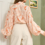 STYLEVAVA orange floral balloon sleeve blouse with tie-neck, model wearing size S